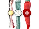 trois montres de couleurs différentes placées l'une à côté de l'autre sur une surface blanche