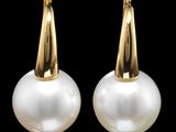une paire de boucles d'oreilles en perles et en or sur fond noir