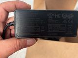 the hand is holding a black charger that is plugged into a box