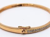 a close up of a gold bracelet with diamonds on it