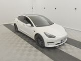 La Tesla Model 3 blanche est garée dans une pièce dont le sol est à carreaux.