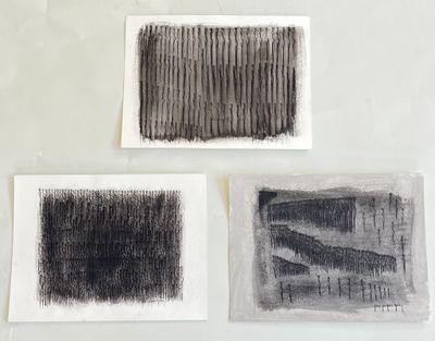 three black and white drawings on white paper on a table