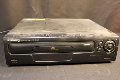 an old cd player sitting on top of a table next to a wall