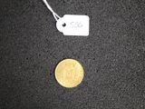a gold coin and a white tag on a black surface