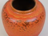an orange vase sitting on a table with a white background