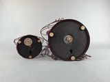 two black and gold clocks sitting next to each other on a white surface