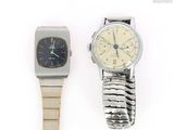 two watches sitting next to each other on a white surface
