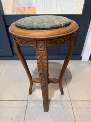 une vieille table en bois avec un plateau en marbre, posée sur un sol carrelé