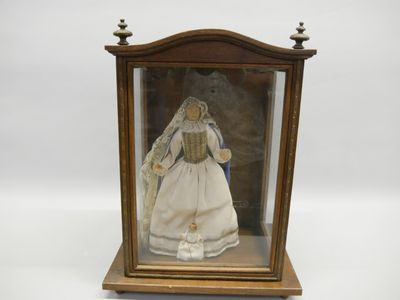 une poupée ancienne dans une vitrine, sur fond blanc