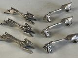 six pieces of silverware sitting on top of a white table