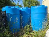 three blue barrels sitting next to each other in the grass
