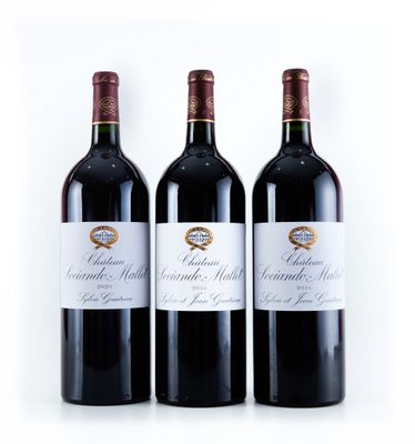 trois bouteilles de vin rouge posées l'une à côté de l'autre sur une surface blanche