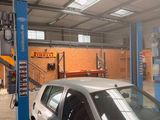 une voiture argentée posée sur un pont élévateur dans un garage