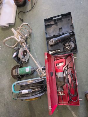 une boîte rouge contenant des outils, posée par terre à côté d'une paire de chaussures