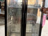 un homme debout devant un réfrigérateur à porte vitrée