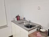 a small kitchen with a microwave, stove, sink, and refrigerator