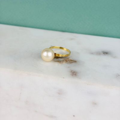 La bague en or avec une perle repose sur une dalle de marbre