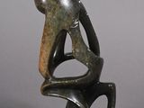 sculpture of a man sitting on a chair with his back to the camera