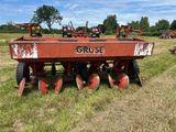 une photo représentant un gros tracteur agricole rouge équipé de quatre herses à disques dans un champ