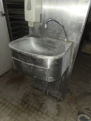 a metal sink in the middle of a dirty room