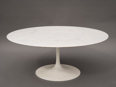 une table en marbre blanc avec un piètement circulaire sur fond gris