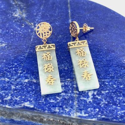 a pair of earrings with chinese writing on them sitting on a blue marble slab