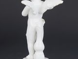 a white figurine of a boy holding a bird on a pedestal
