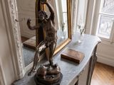 une statue représentant une femme assise sur une table devant un miroir