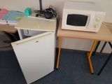 two microwaves sitting on a small table next to each other