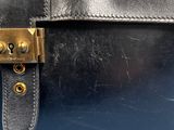 the back of a black purse with a gold buckle on it