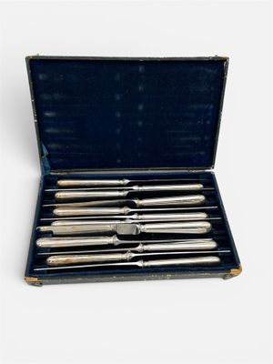 un coffret contenant six pièces d'argenterie, posé sur un support blanc