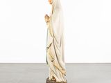a statue of a woman in a white robe holding a rosary