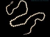 un collier de perles blanches muni d'un fermoir en argent, sur fond noir
