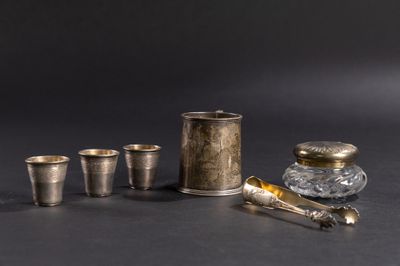 cinq tasses en argent et une cuillère en argent posées sur une table