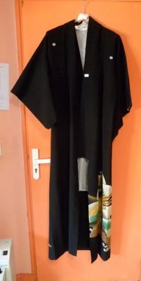 une robe noire accrochée au mur près d'une porte