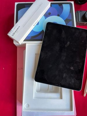 a box with a pen, a camera, and a tablet on a table