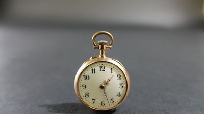 une petite montre de poche en or posée sur une table
