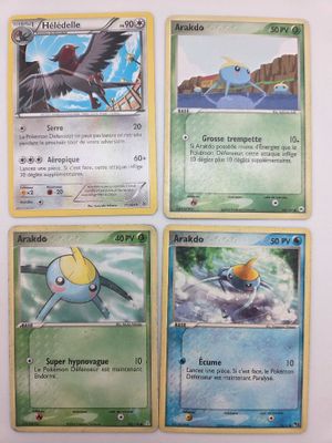 Quatre cartes Pokémon sont représentées sur une surface blanche