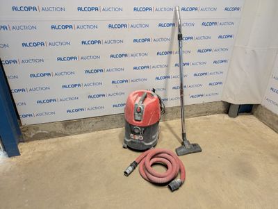 un aspirateur et un tuyau posés par terre devant un mur