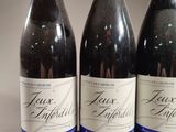 three bottles of wine are lined up on a table