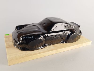 une voiture enrobée de chocolat posée sur un bloc de bois