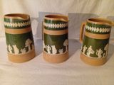 trois tasses vertes et marron posées sur une table blanche