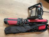 un trépied rouge et noir et un sac noir et rouge posés sur un plancher en bois