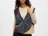 Cette femme porte un gilet en tricot et un pantalon noir.