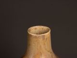 a brown vase sitting on a table with a black background