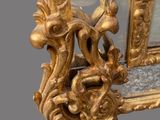 a mirror that has a gold frame with a bird on it