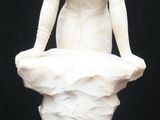 a white statue of a woman sitting on a rock