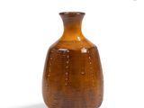 a brown vase that is sitting on a white surface