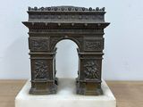 statue of a bronze arch on a marble base on a wooden table