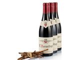 three bottles of red wine sitting next to a bundle of sticks